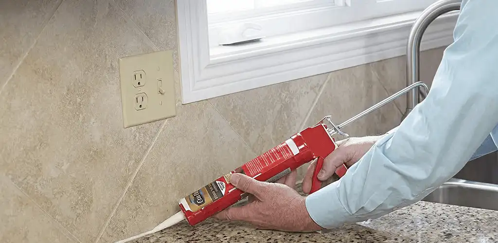 Handyman applying caulk along a kitchen backsplash and countertop seam in Kansas City, MO