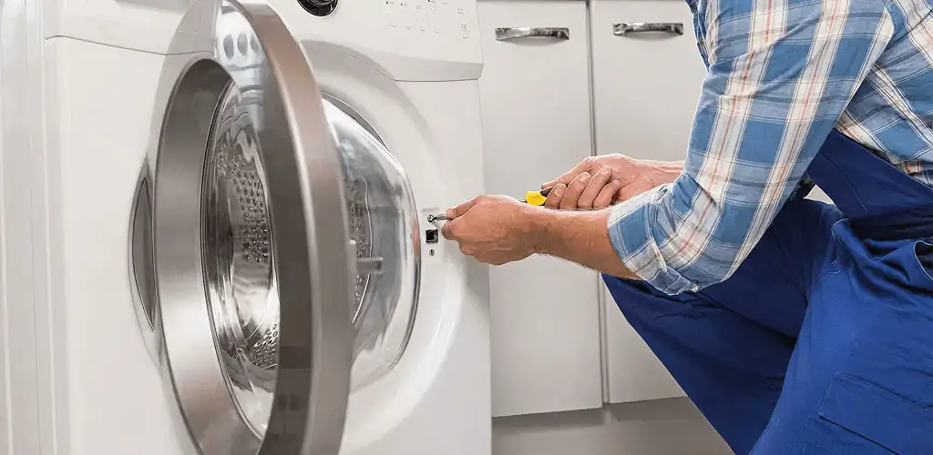 Handyman repairing a clothes dryer and checking electrical connections in Kansas City, MO