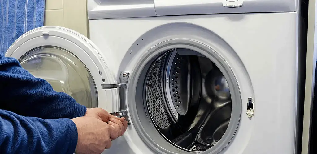 Washing machine repair handyman checking a front-load washer door and latch in Kansas City, MO