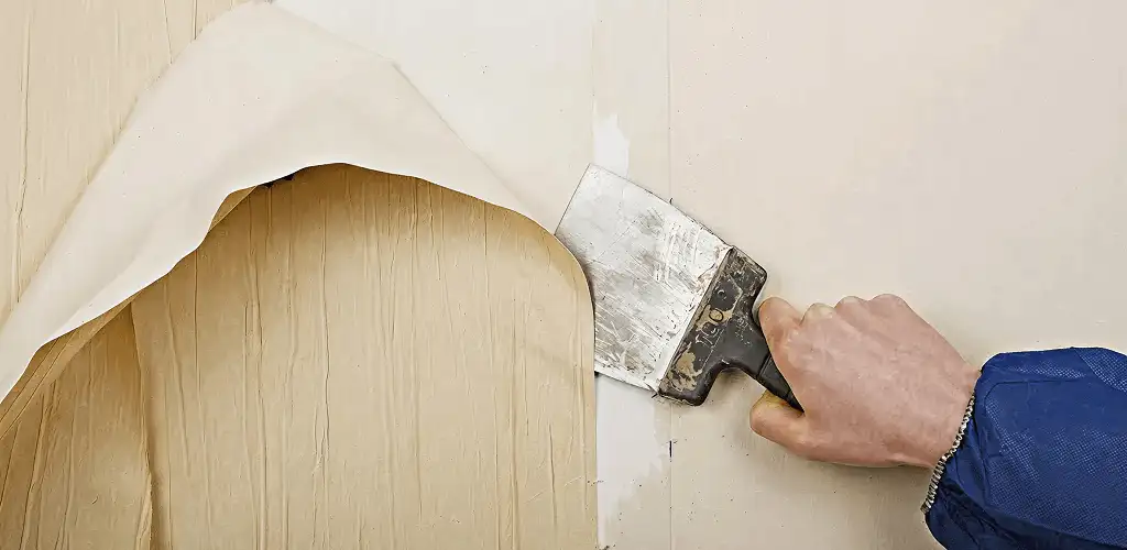 Handyman removing wallpaper with a scraper for wall preparation in Kansas City, MO