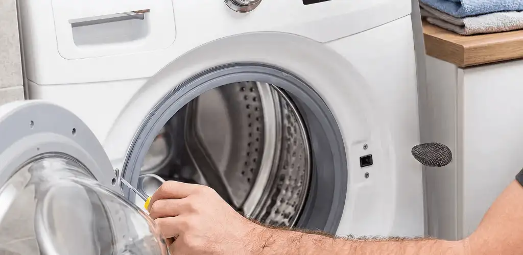 Handyman repairing a front-load washing machine and inspecting the drum in Kansas City, MO