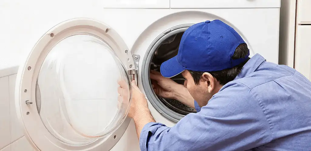 Washing machine repair handyman inspecting a front-load washer drum in Kansas City, MO