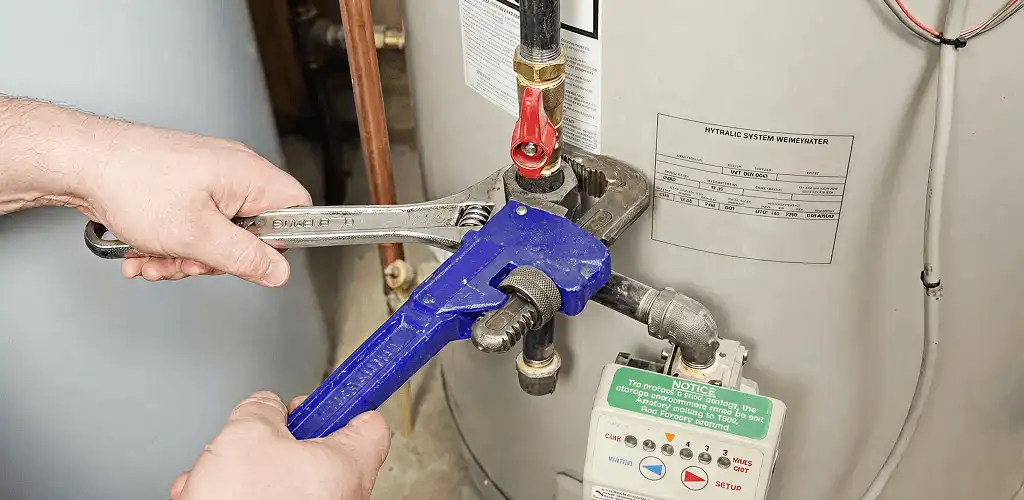 Water heater repair technician tightening the shutoff valve and supply line in Kansas City, MO
